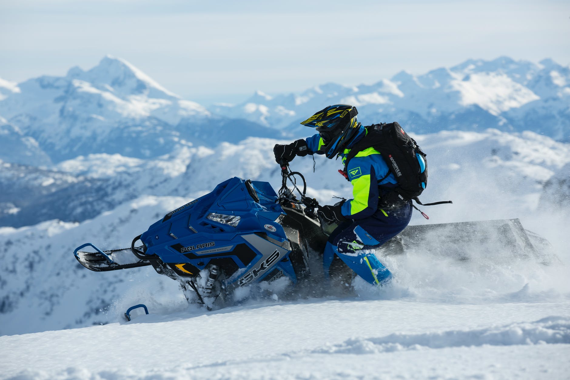 man in blue and green long sleeved suit riding on snowmobile