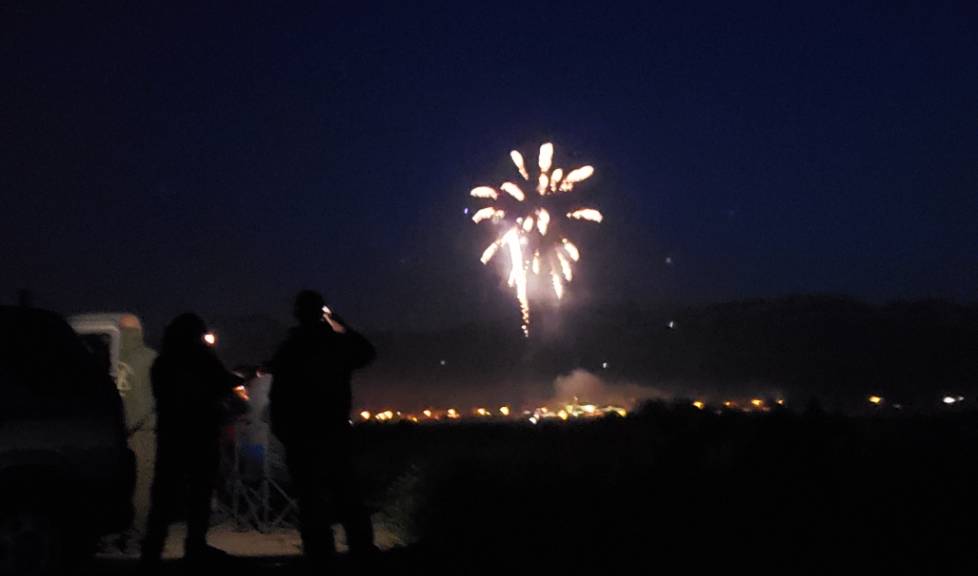 people watching fireworks in the dark with a car in the background