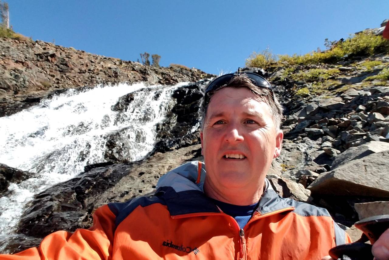 a man taking a selfie in front of a waterfall