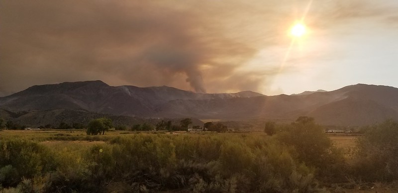 the sun is shining over a mountain range with smoke