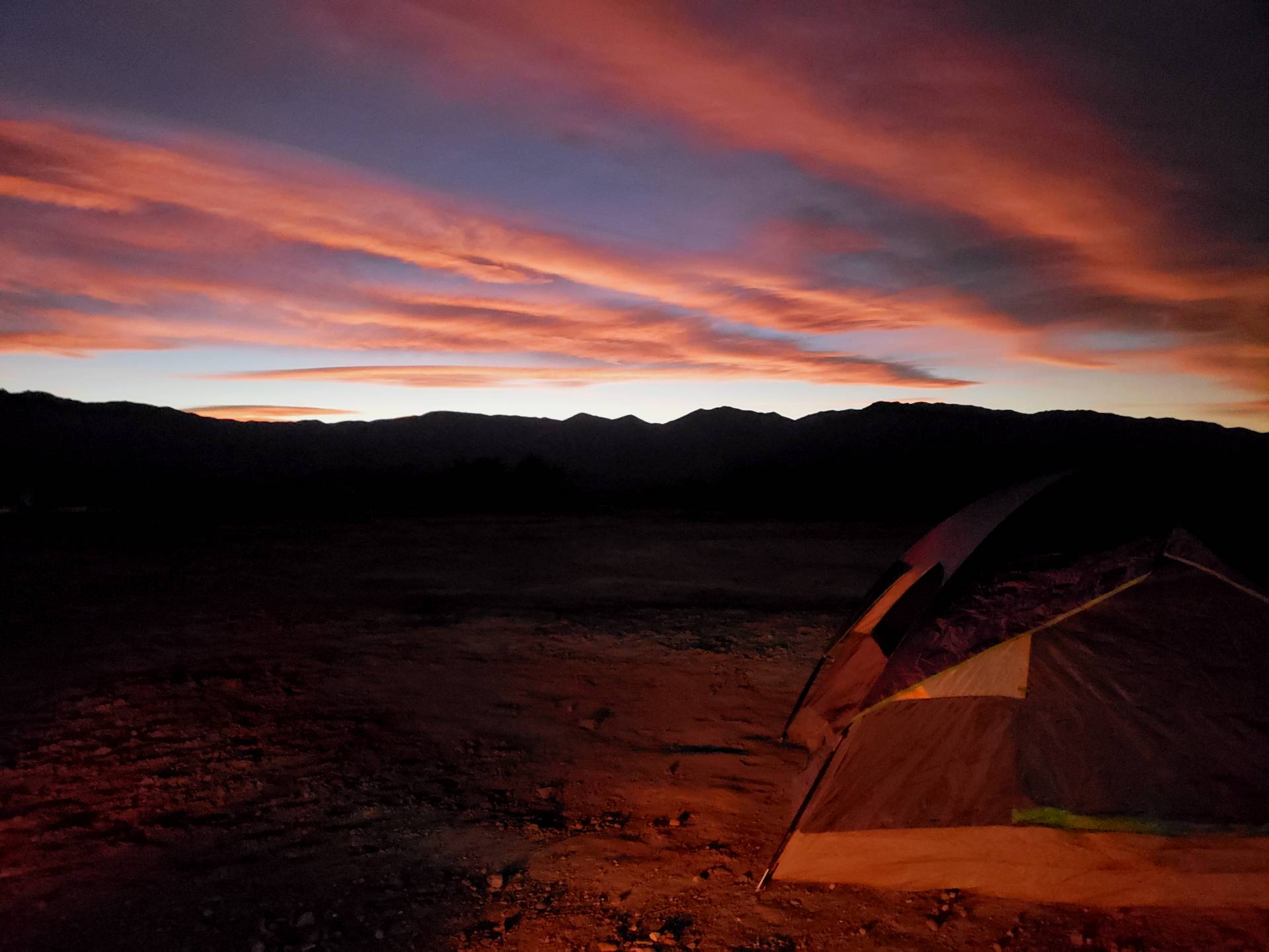 a tent is lit up at sunset in the desert