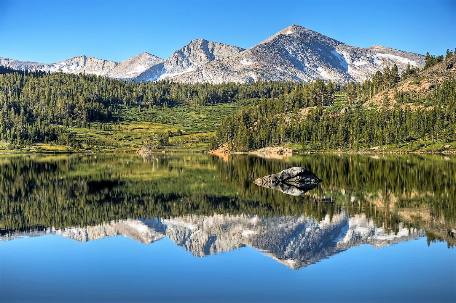 mountains reflected in a lake with trees and rocks
