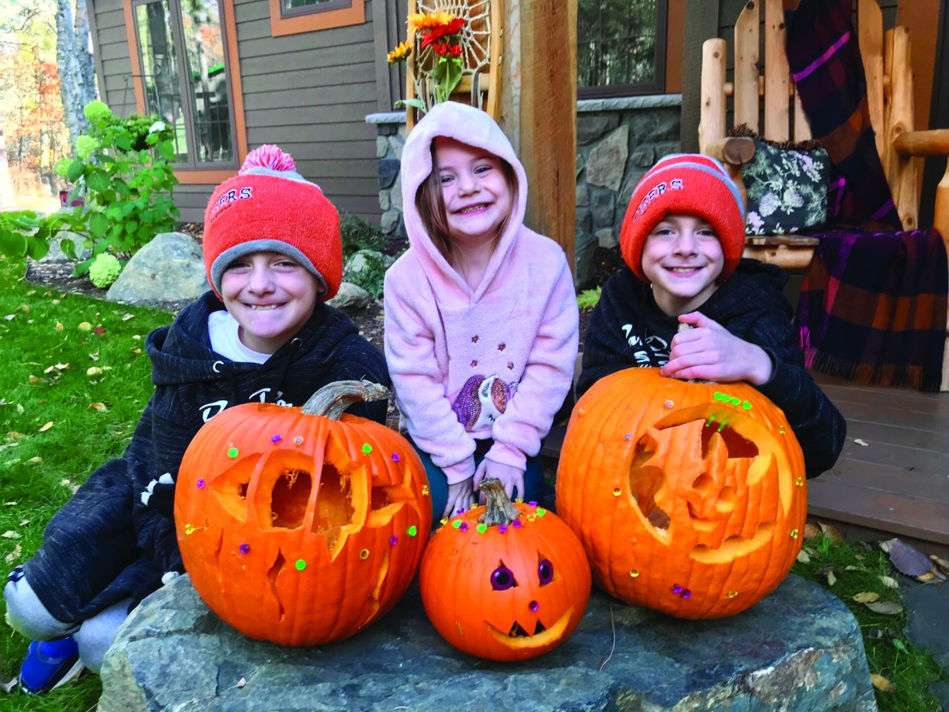 Three kids with big smile with carved pumpkins and costumes