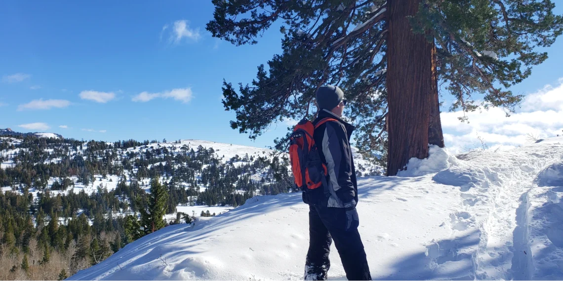 Young Man looking up mountain in snow