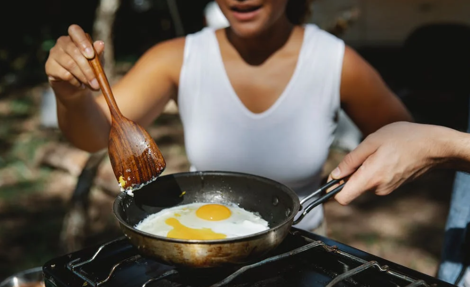 girl cooking eggs outdoors