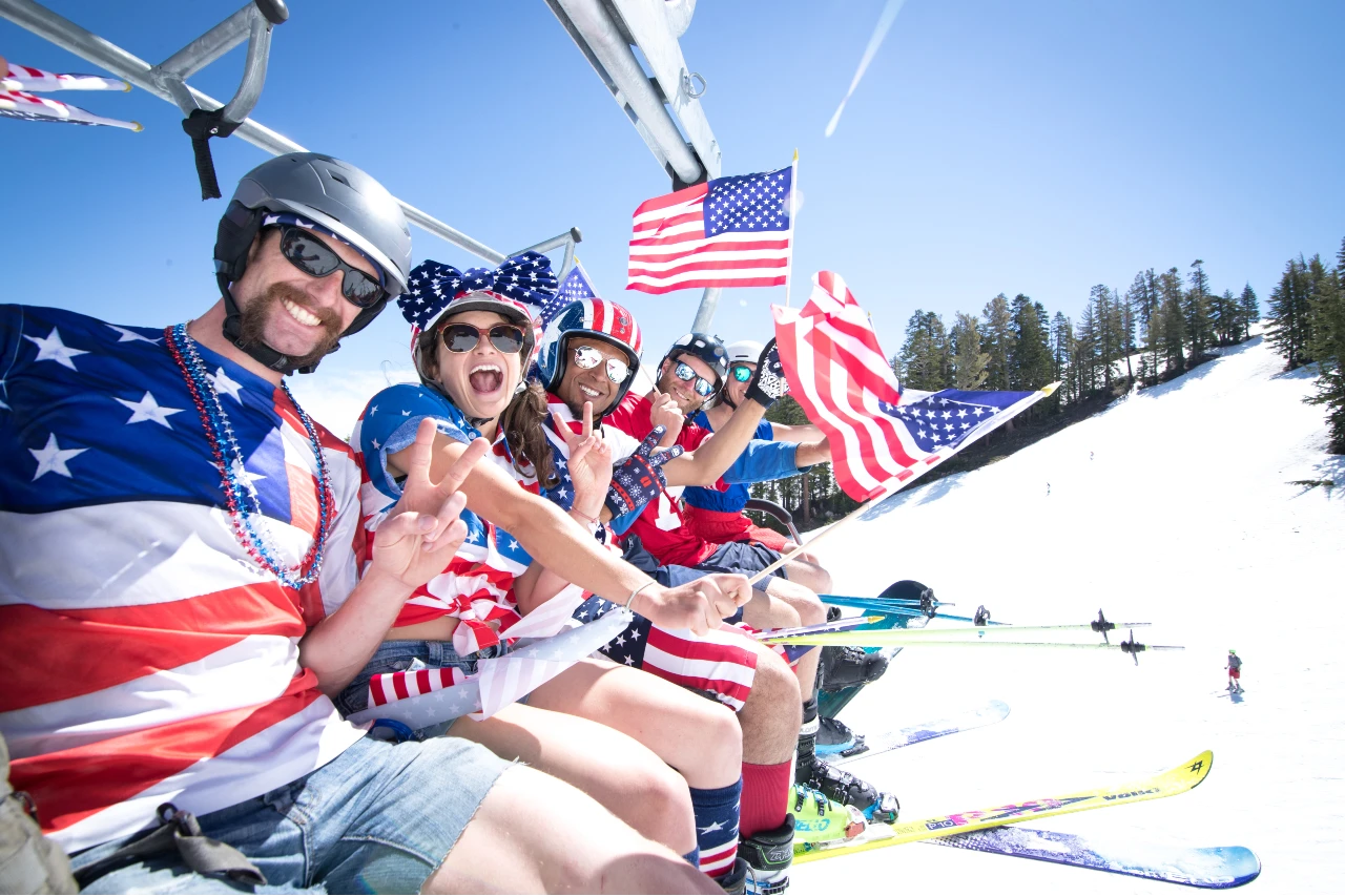 Guys and girls waving flags riding chairlift