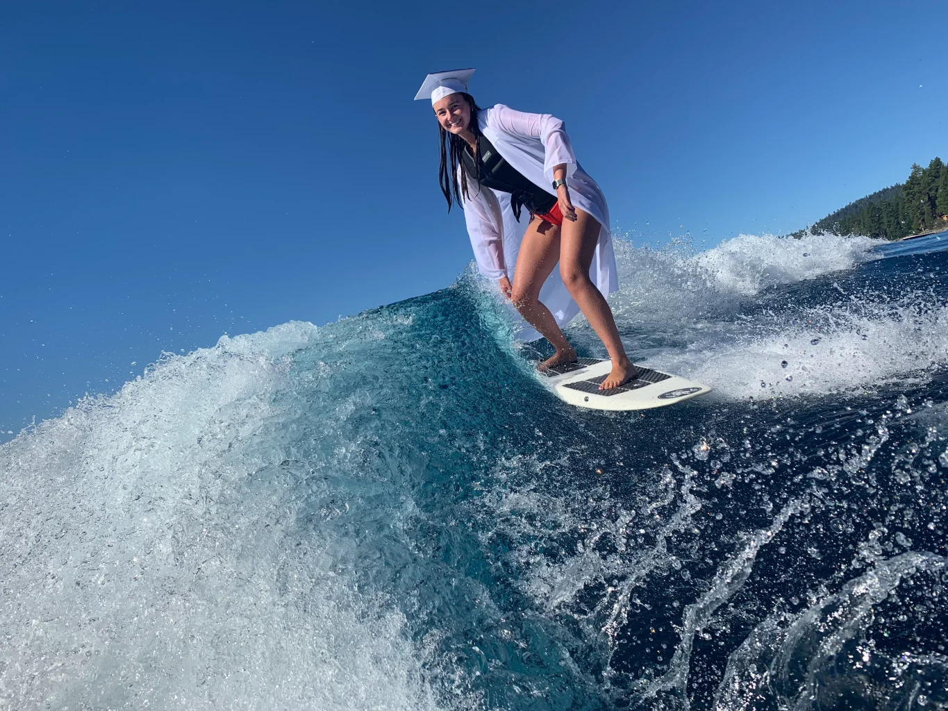 Girl surfing Lake almanor in graduation gear