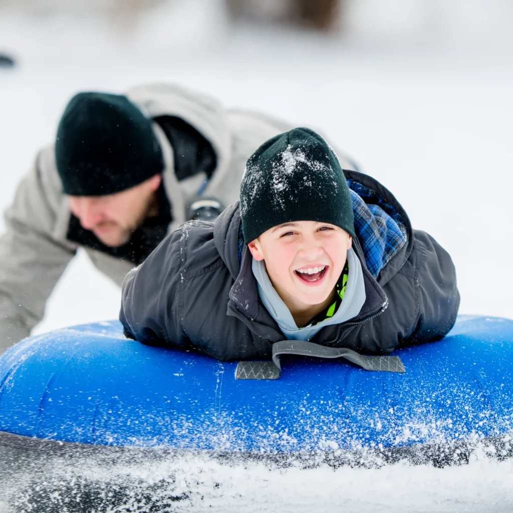 Young man Tubing in winter big smile